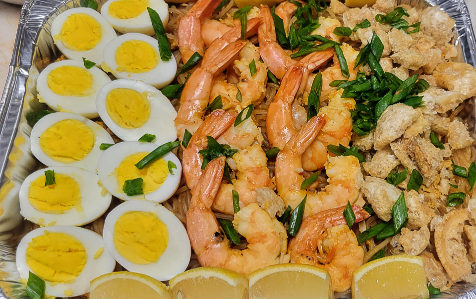 Catering dish of Palabok with eggs, shrimp, noodles, and chicharon